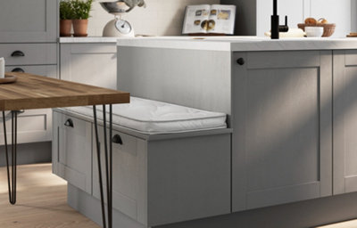 Slate grey shaker kitchen island with integrated bench seating and cushion, marble-effect worktop, black tap, wood breakfast bar, and matching cabinetry with black cup handles.