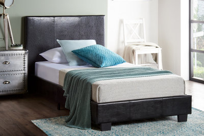 A black leather-look fabric single bed in a cosy bedroom space.