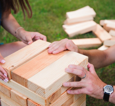 Two people playing wooden giant Jenga in a garden.