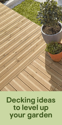 A brown deck a summers day, with plant pots and grass visable