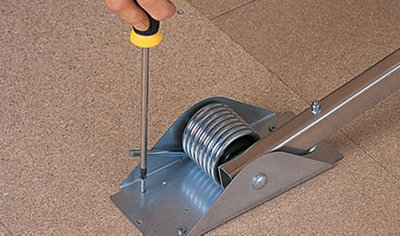 Person using a screwdriver to secure a loft hatch power pivot arm to the loft floor.