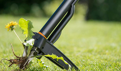 Close up of the bottom of a weed puller gripping a weed that it has just pulled out of the ground.