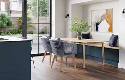 The Garcinia kitchen’s matt slab doors with integrated handles are shown here as smart bench seating, bringing contemporary design and cohesive colour into the dining space.