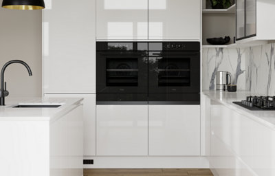 Gloss slab kitchen doors with integrated handles, creating a sleek, modern look with black appliances and a marble-effect splashback.