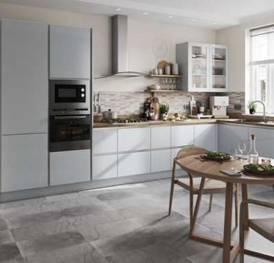 Large grey and wood Scandi style kitchen with grey floor tiles and a round wooden dining table.