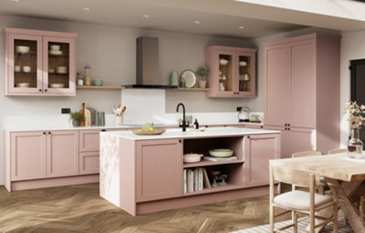 Contemporary antique rose shaker kitchen with a central island, white worktops, glazed wall cabinets, black tap and handles, open shelving, and herringbone wood-effect flooring.