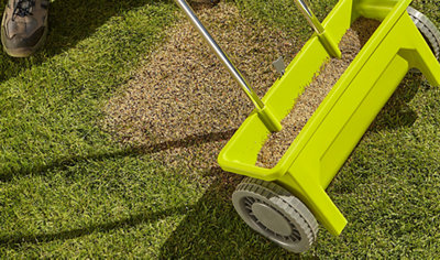 A lawn spreader spreading fertiliser across a lawn.