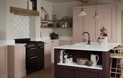 The Tydeman kitchen, featuring shaker style cabinets in a atinque light pink with a kitchen island in a deep purple colour, with silver coloured handles. The kitchen features a mix of white marble-effect countertops.