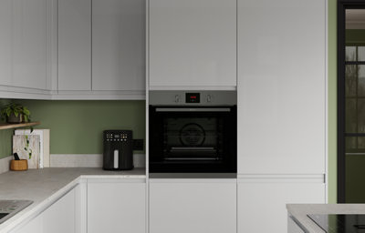 The Garcinia kitchen in gloss dove grey, featuring sleek slab cabinet doors with integrated handles, a built-in oven, and a green painted splashback with a stone-effect worktop.