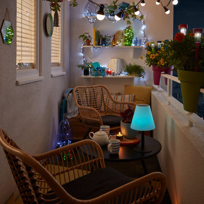 A cosy balcony at night, lit up by bright fairy lights in coloured bottles