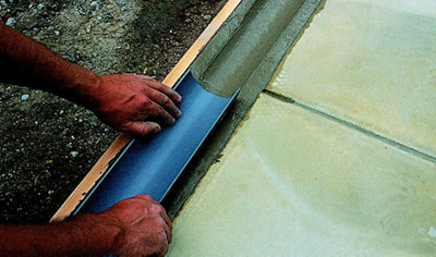 Pressing a piece of guttering into wet concrete to leave the shape of the guttering in the surface.