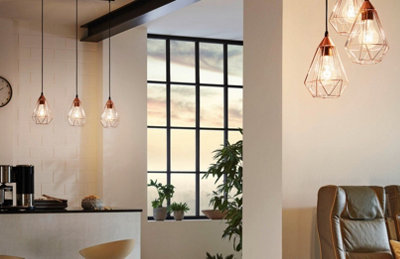 Three copper-effect geometric wire pendant lights hanging over the kitchen in the background, with a cluster of three at varying heights in the living area.