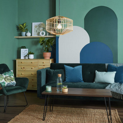 A green living room with a painted wall mural of four curved arches in blue, cream and dark green.