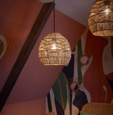 A close up of two rattan lampshades hanging from the ceiling in a bedroom, the lights are on, casting a soft glow throughout the space.
