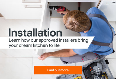 Installer using a power drill to fit a kitchen unit, with the word “Installation” overlaid on the image.