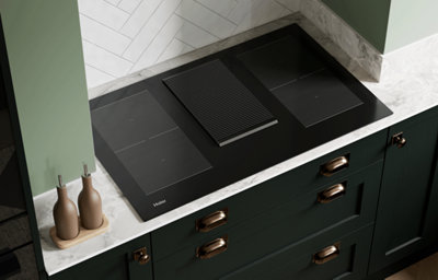 The Tydeman kitchen, featuring shaker style cabinets in a dark shade of green. Cabinets are paired with brass hardware, and marble-effect countertops feature on the kitchen worktop, splashback, and envelope the kitchen island.