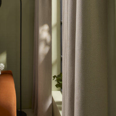 Close-up of soft neutral curtains showing textured fabric and gentle folds, with natural light filtering through.