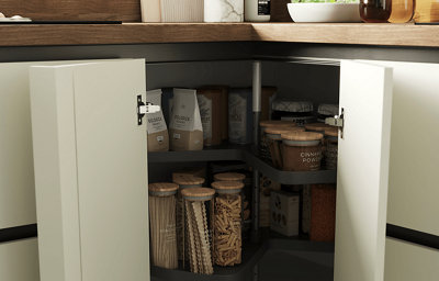 A close up view of an opened corner kitchen cabinet showing various food stored inside.