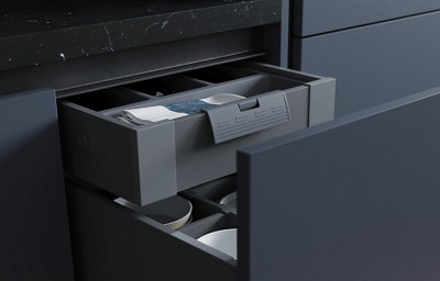 A close up of a black built-in oven surrounded by matt blue cabinets and wooden worktops.