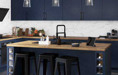 Kitchen featuring multiple vlue slab units with dark handles and wooden worktops, with a marble and honeycomb effect wall pattern.