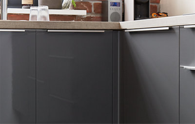 The glossy finish of the dark grey cabinets adds light and shine. The silver-coloured metal handles also glisten in the light.