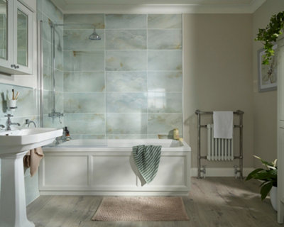 A bathroom with light grey tiles, beige walls, and traditional plumbing fixtures.