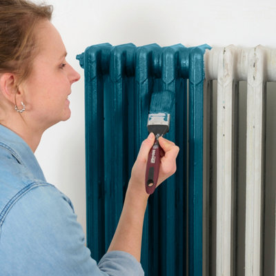 A person is painting a radiator blue.