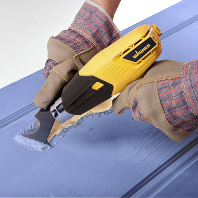 A person is using a heat gun to remove paint from a door.