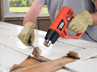 A person is using a heat gun to remove paint from a door.