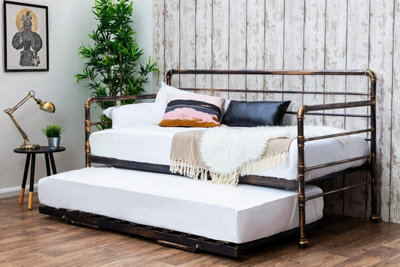 A metal guest bed consisting of a single bed, with an additional single mattress that slides out from underneath.
