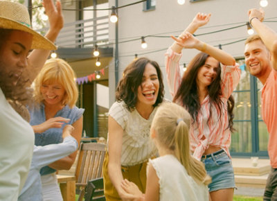 Small group of people smiling and dancing together in a garden.
