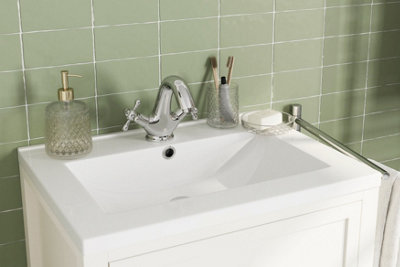 Green pastel coloured tiles behind a white basin.