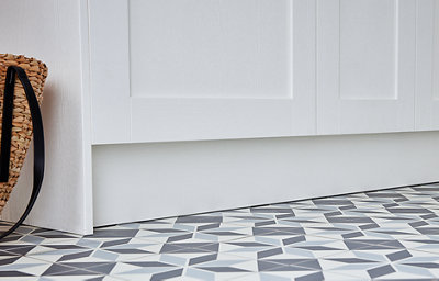 Close-up of ivory kitchen cabinets and plinths, with geometric patterned blue and white floor tiles
