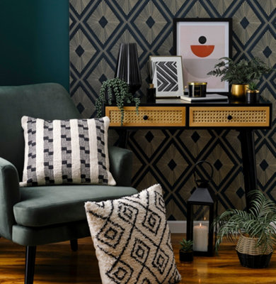 Art deco geometric teal and gold wallpaper in a living room with a green armchair and white and black geometric cushions.