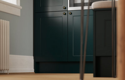 Shot from a low angle, light from a window hits the dark green shaker kitchen cabinets. With some areas still in shade, the matt finish provides a uniform look in all light.