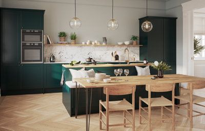Kitchen featuring dark green shaker cabinets, built-in appliances and a marble-effect splashback. A long rectangular wooden table with hairpin legs is surrounded by wooden chairs and a kitchen island featuring a sink and built-in bench seating.