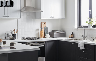 Kitchen featuring dark grey shaker cabinets that contrast against the bright white walls, tiled splashback and worktop. Stainless steel and silver coloured hardware complete the look.