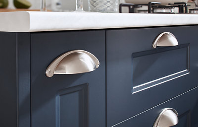 A close up look at the matt finish of the Artemisia matt finish dark blue shaker cabinets. Light and shadow reveals a uniform finish in any light. The silver coloured handles shine in the light.