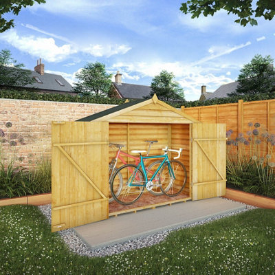 A wooden bike store in a garden, there are two bikes in the bike store.