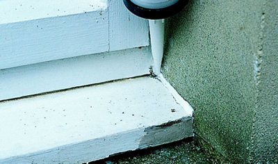 Using a sealant gun to apply sealant to the gap between a wall and a timber windowsill.