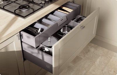 A deep shaker-style kitchen drawer in light grey is open to reveal clever storage. The drawer door front houses two drawers - at the bottom a drawer deep enough for pots, and a top drawer with a pull tab that houses cutlery.