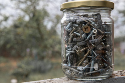 Screws being stored inside labelled glass jar.