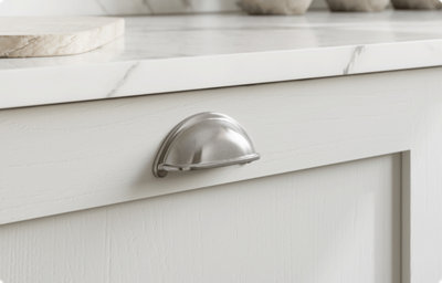 The light grey shaker style kitchen cabinet has a brushed chrome handle in a semi-circle shape. The bottom of the semi-circle is hollow to allow you to pull the cupboard door open.