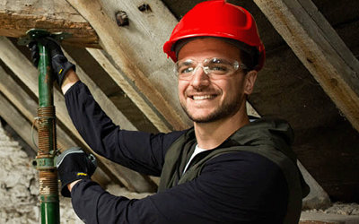 Builder working in roof space with acro props