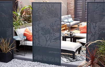 This image depicts a garden living setting outside, with garden furniture and garden tables. There is a small privacy screen shown, with spial patterns partially blocking the garden living area.