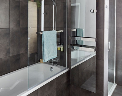 A glass bath screen with a towel rail in the centre installed on a straight shower bath.