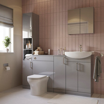 Pink tiled bathroom featuring a built-in grey storage unit with cupboards, integrated sink, and toilet.