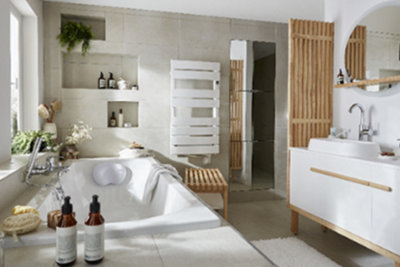 A bright bathroom with a white bath and sink, and wooden screen and bath mat.