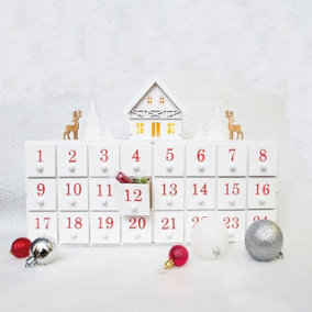 Battery Powered White Wooden Advent Calendar - Light Up Xmas Decoration with Christmas Carvings & 24 Drawers - H27 x W43 x D6.5cm