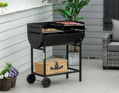 A small black BBQ in a small grey paved garden.